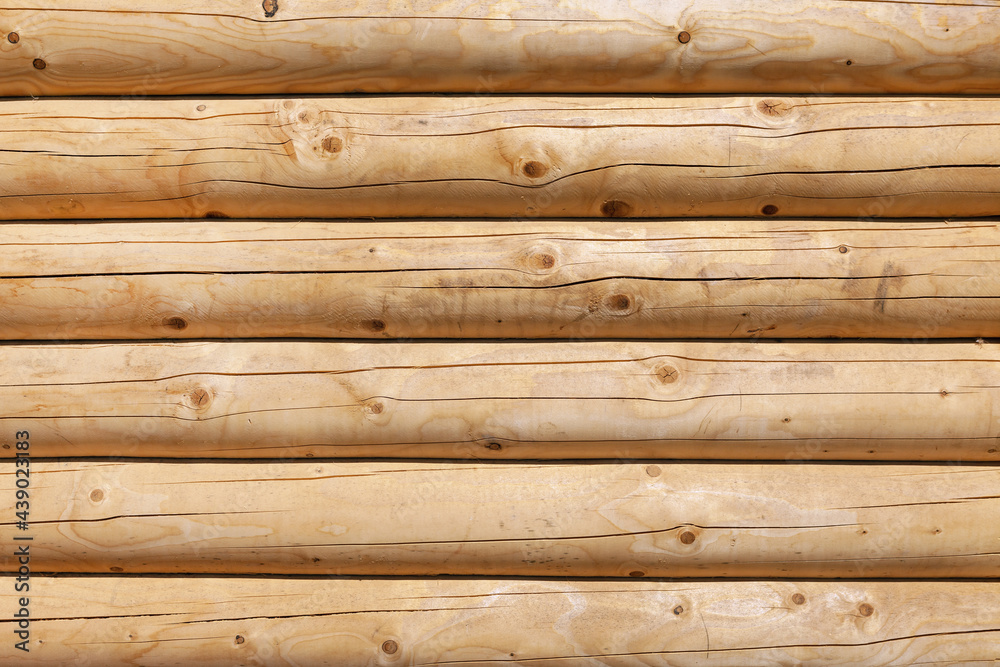 Modern, new, clean log wall made of round logs of natural color Modern, new, clean log wall made of round logs of natural color