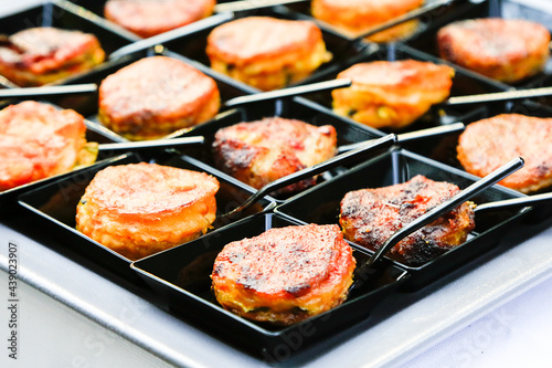 fingerfood closeup. small backed oriental snacks on square black plates with tiny spoons. Catering layout. Gourmet food degustation. Menu concept picture. Healthy dieting. corporate party snacks