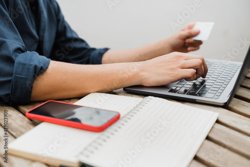 Business man doing online shopping with credit card using laptop computer outdoor - Focus on right hand