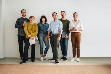 Happy colleagues standing against wall in office