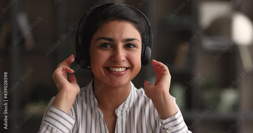 Young Indian woman sit indoor wear headset makes speech on camera, close up. Female blogger record video blog, tell advice for internet audience, share skill, experience. Videocall remote talk concept Young Indian woman sit indoor wear headset makes speech on camera, close up. Female blogger record video blog, tell advice for internet audience, share skill, experience. Videocall remote talk concept