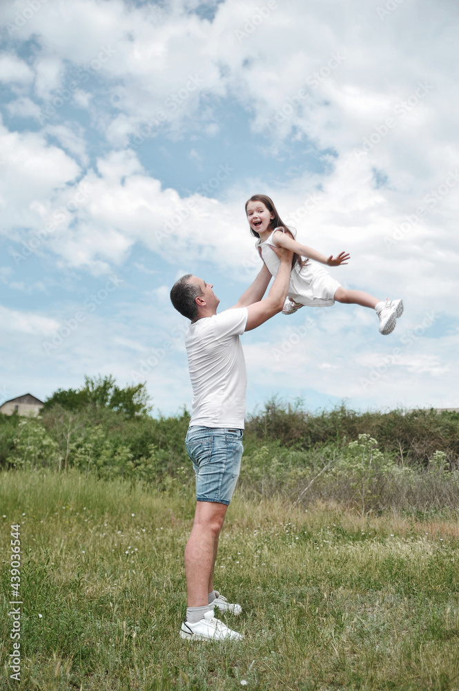 Dad throws his daughter into the sky. Happy family concept. Dad and daughter have fun in the field Dad throws his daughter into the sky. Happy family concept. Dad and daughter have fun in the field