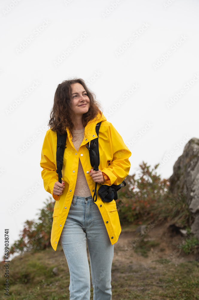 Young woman on a mountain hike. Woman in yellow rain jacket