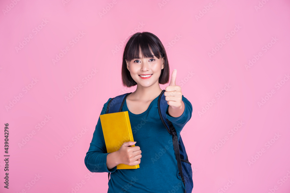 Asian Student girl smiling thumbs up smart holding books bag pack reading learning research studying information communication, pink isolated background school college university academic education Asian Student girl smiling thumbs up smart holding books bag pack reading learning research studying information communication, pink isolated background school college university academic education