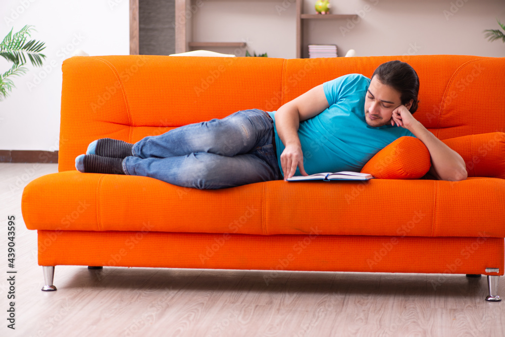 Young male student sitting on the orange sofa Young male student sitting on the orange sofa