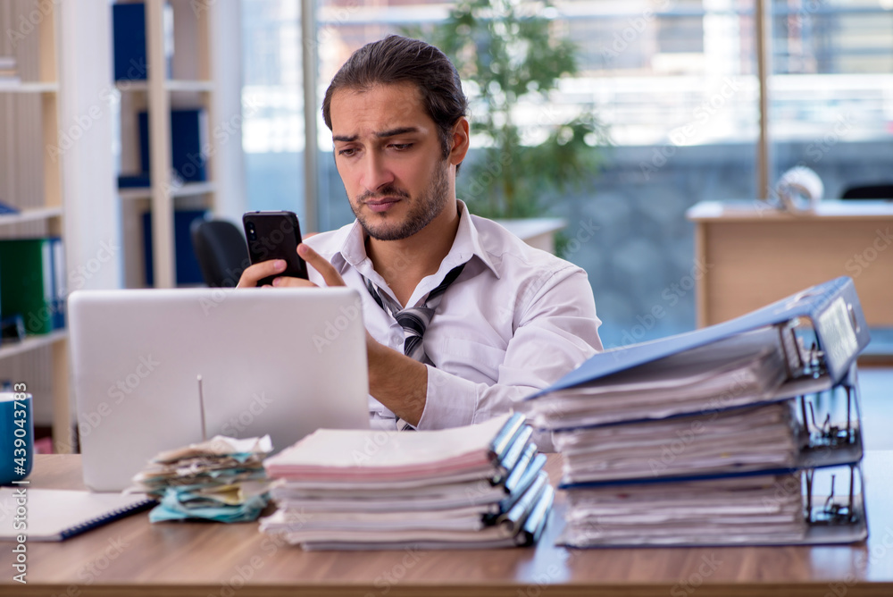 Young male employee unhappy with excessive work in the office