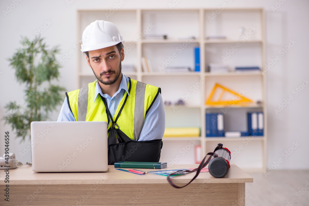 Young arm injured male architect working in the office Young arm injured male architect working in the office