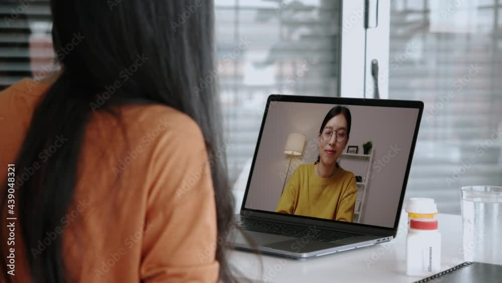 Asian businesswoman talking to colleague team in a video conference at home during COVID-19 pandemic. Self-isolation, social distancing, quarantine at home. Smart working from home. Asian businesswoman talking to colleague team in a video conference at home during COVID-19 pandemic. Self-isolation, social distancing, quarantine at home. Smart working from home.