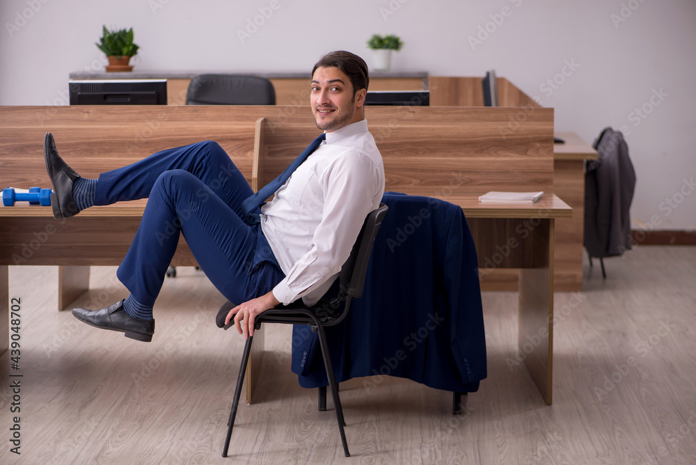 Young businessman employee doing sport exercises at workplace Young businessman employee doing sport exercises at workplace