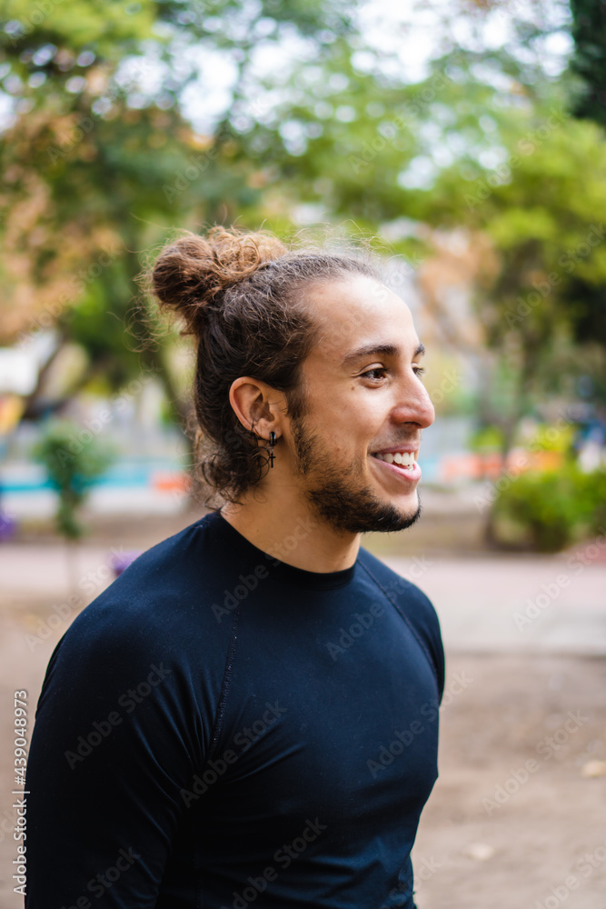 profile portrait of a young Brazilian long-haired man in a park outside laughing profile portrait of a young Brazilian long-haired man in a park outside laughing