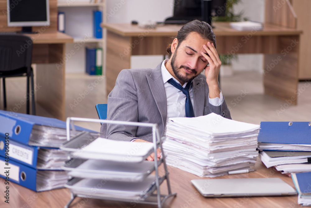 Obraz premium Young businessman employee unhappy with excessive work in the of