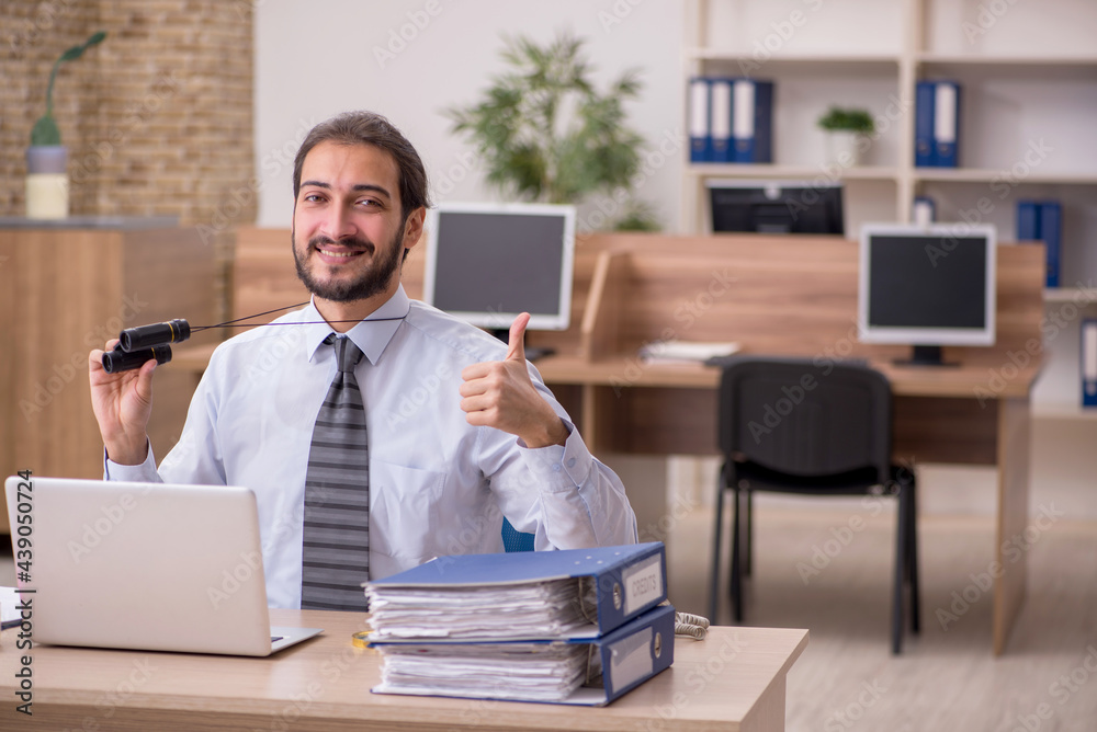 Obraz premium Young male employee holding binoculars in industrial espionage c