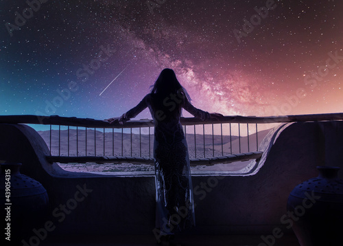 Dubai, United Arab Emirates, Woman in luxury resort in desert watching falling star at starry sky at night