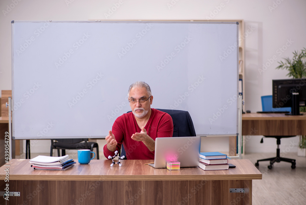 Old teacher physicist sitting in the classroom