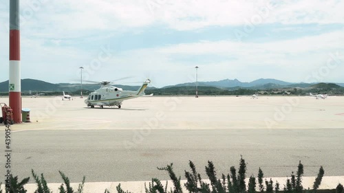 Slow motion video of an helicopter taking-off from an airport runway. OlbiaAirport is the second largest airport in Sardinia, Italy. photo