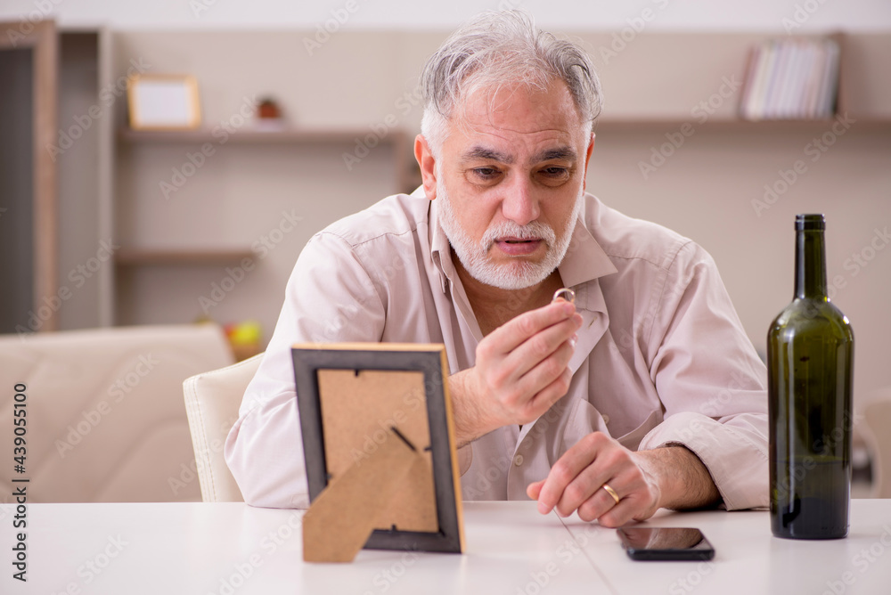 Old widower drinking alcohol at home Old widower drinking alcohol at home
