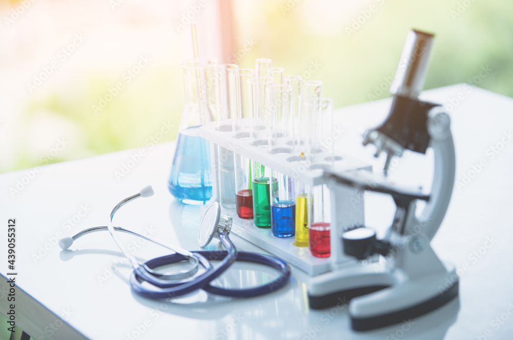Fototapeta premium Microscope and colorful test tubes on table in Laboratory. Science chemistry concept. Blue tone