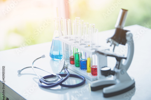 Microscope and colorful test tubes on table in Laboratory. Science chemistry concept. Blue tone