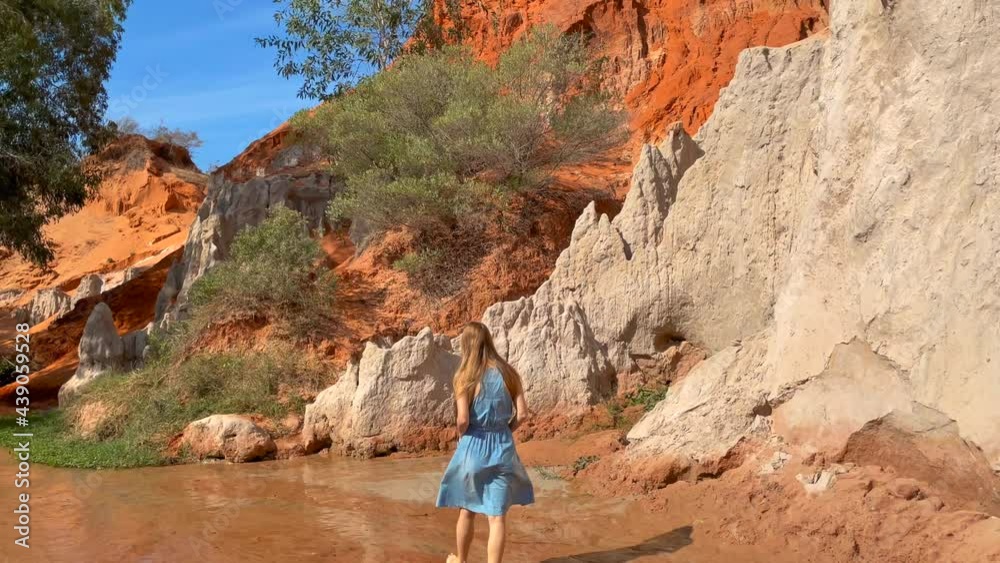 Slowmotion shot. A woman tourist is visiting the red canyon or Fairy stream at the border of desert in the Mui Ne village in southern Vietnam. Shot on a phone Slowmotion shot. A woman tourist is visiting the red canyon or Fairy stream at the border of desert in the Mui Ne village in southern Vietnam. Shot on a phone