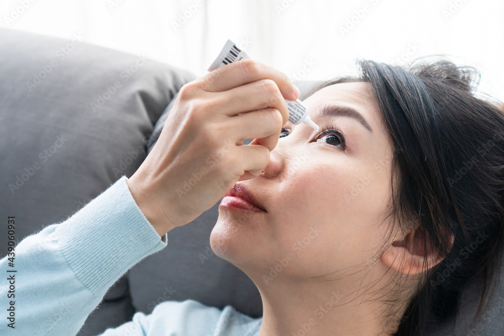 Naklejka premium Young Asian woman uses eye drops for eye treatment. Redness, dry eyes, allergy and eye itching. Vision and ophthalmology medicine concept.
