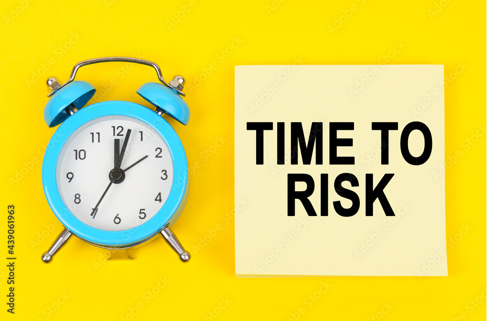 On a yellow background lie a clock and a sticker sheet with the inscription - TIME TO RISK