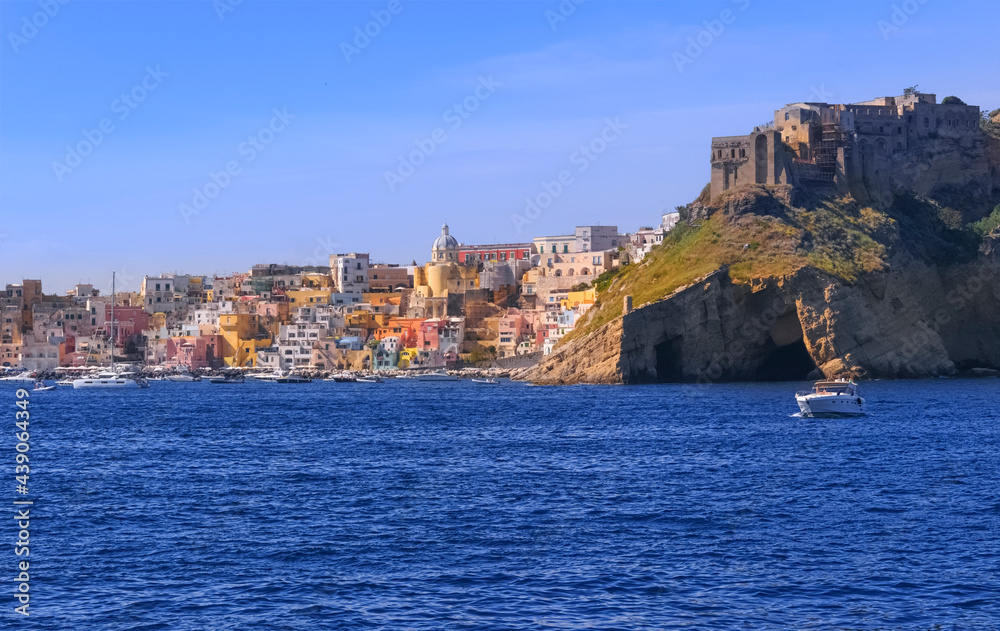 Panoramic view of Procida, Italian Capital of Culture 2022: colorful houses, cafes and restaurants, fishing boats and yachts in Marina Corricella , in Gulf of Naples, Campania, Italy.