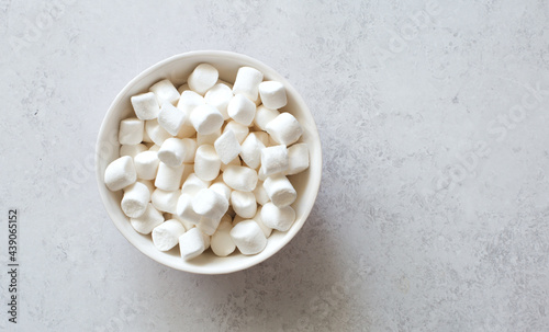 White marshmallows in white bowl close up. Flat lay