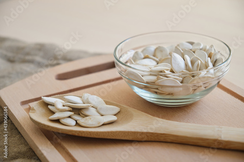 Pumpkin seeds in white bowl and spoon on the flax on the table