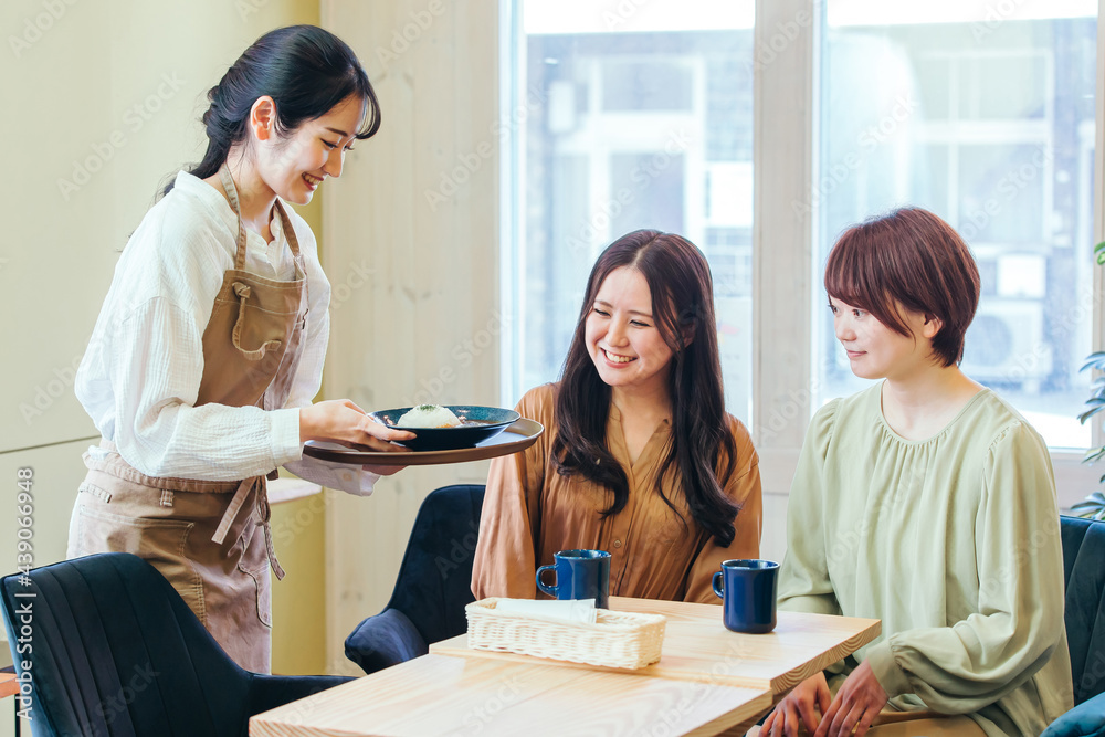 カフェ・飲食店にきた女性たちとホールスタッフ
