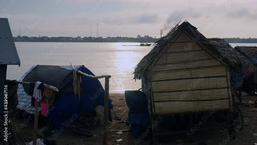 Sunset view over Mekong river from the fishing village on the riverbank. Barge sailing in the background Sunset view over Mekong river from the fishing village on the riverbank. Barge sailing in the background