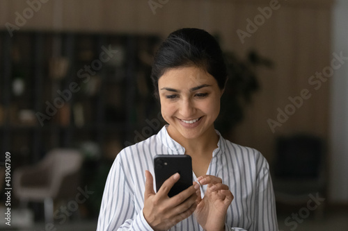 Pleasant messaging. Happy young indian woman modern smartphone user chatting texting dating with beloved man online at social network. Smiling teenage female holding virtual dialogue with good friend