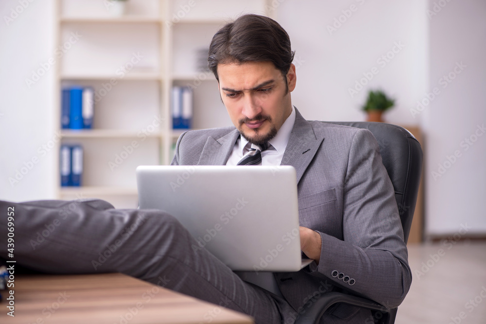 Young attractive male employee sitting at workplace Young attractive male employee sitting at workplace