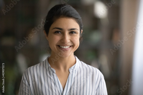 Profile picture of cheerful young female businesswoman student posing indoors. Headshot portrait of friendly casual indian lady office employee consultant look at camera able to help assist customer photo