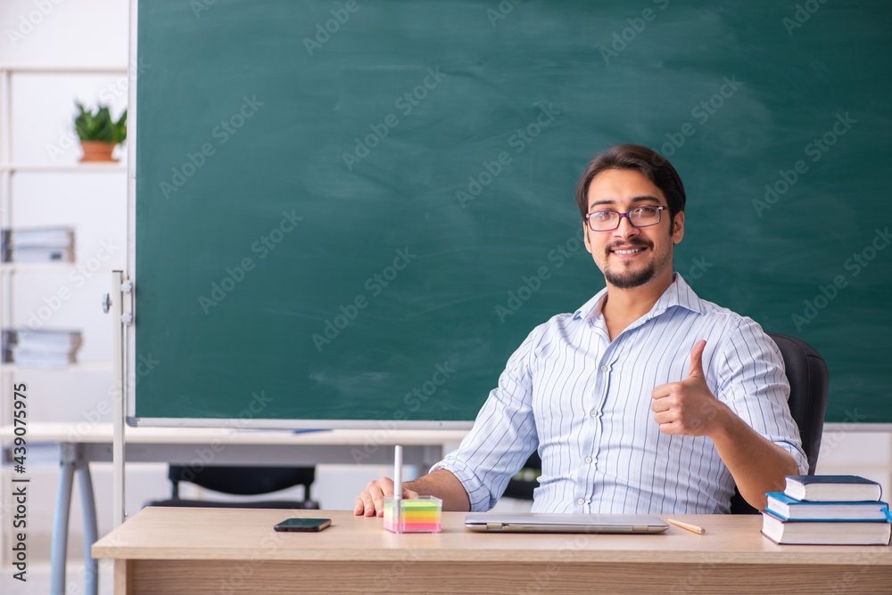Young male teacher in front of blackboard Young male teacher in front of blackboard