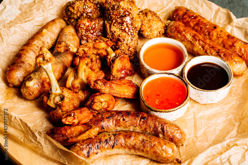 Assorted meat on a large plate with sauces.