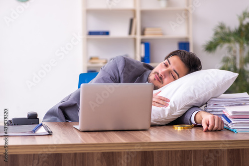 Young male employee in oversleeping concept