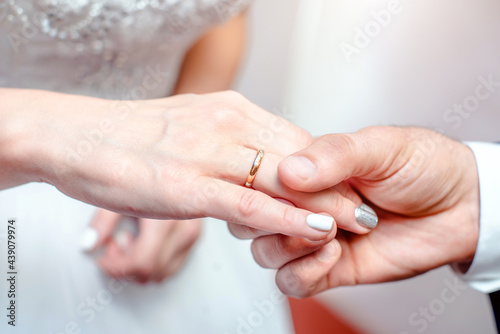 The groom puts a wedding ring on the bride's hand