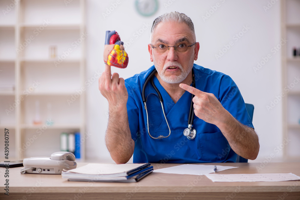Old male doctor cardiologist working in the clinic Old male doctor cardiologist working in the clinic