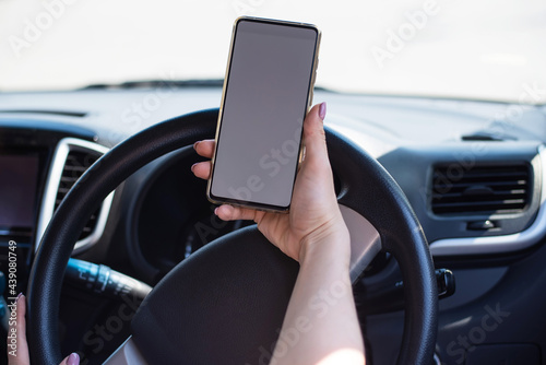 A faceless woman uses a mobile phone while driving a car. The girl uses the navigation in the smartphone