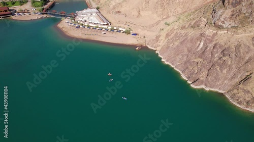 A group of people ride sup surfing in the lake. Aerial view from the drone of the green water and rocky beaches. Inflatable sapboard board. Trees and bushes grow on the bank of Kapchagai. photo