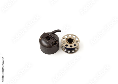 фотографія Sewing machine bobbin and bobbin case isolated on white background
