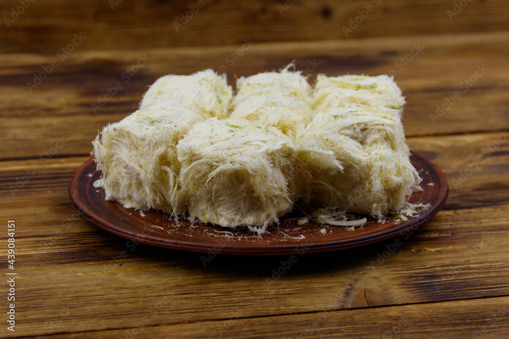 Traditional Turkish dessert Pismaniye with pistachios on wooden table Traditional Turkish dessert Pismaniye with pistachios on wooden table