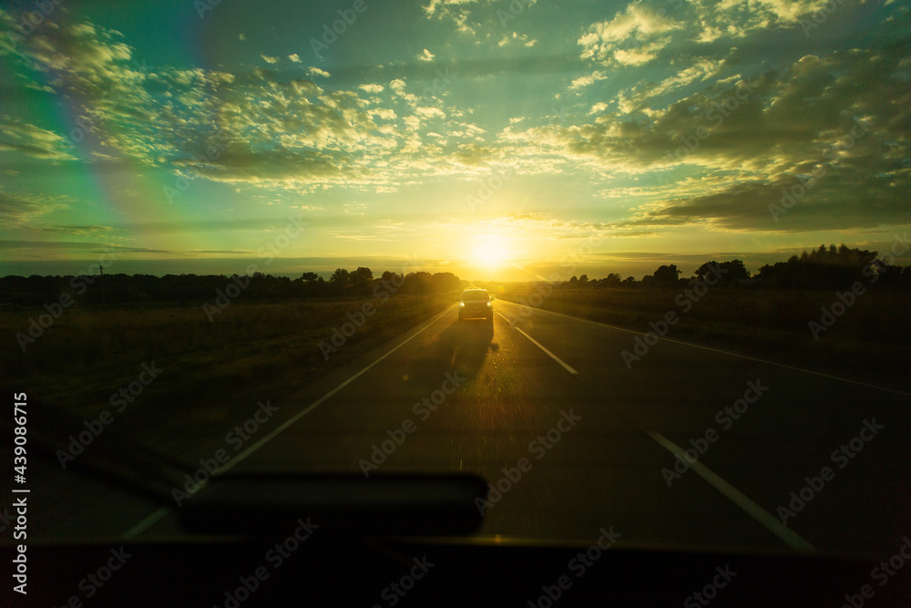 Lonely car drives on the road against the background of sunset