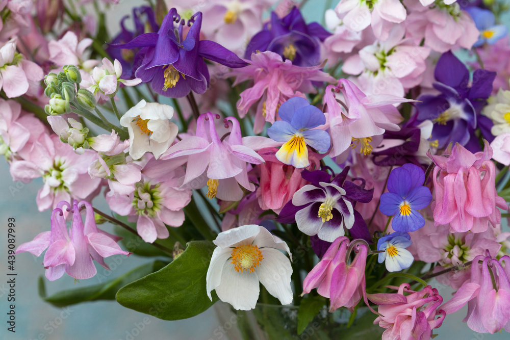 Naklejka premium Background with a bouquet of spring and summer bright pink, white and purple flowers, levkoy, matthiola, anemone, pansies. Close-up, blur, postcard.