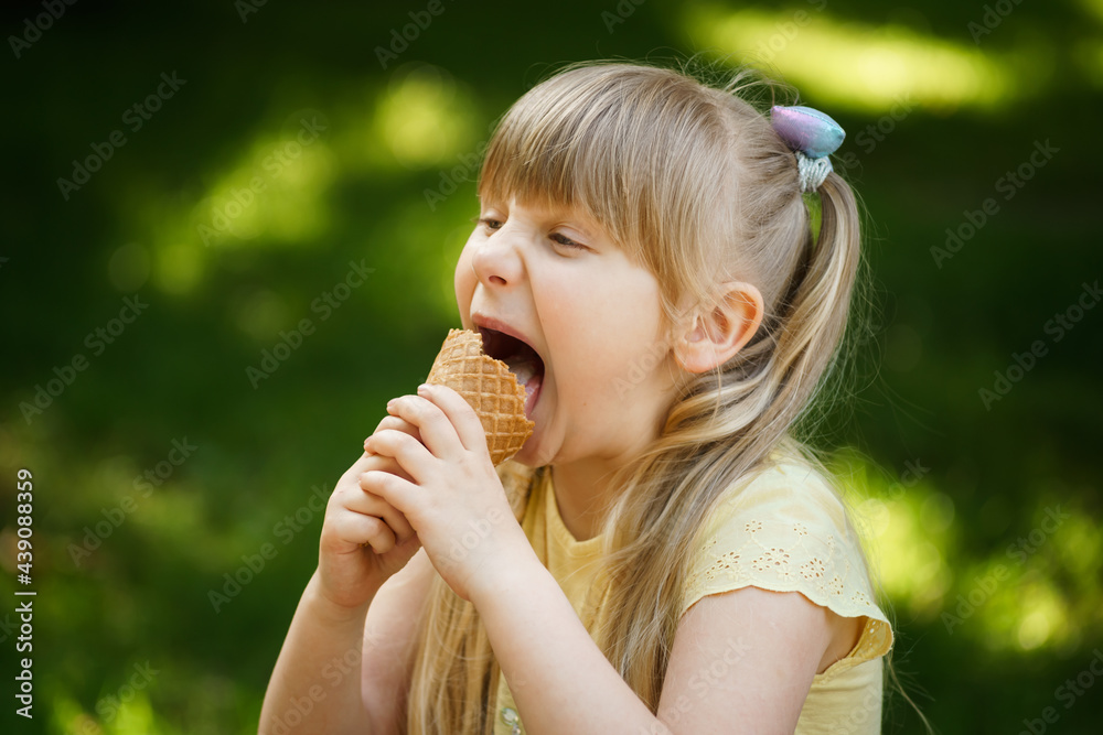 blonde girl in a yellow t-shirt eats ice cream in a green park on a bench blonde girl in a yellow t-shirt eats ice cream in a green park on a bench