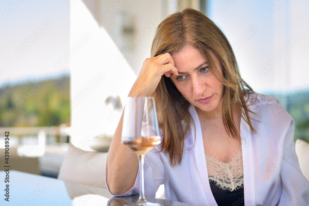 Depressed woman sitting thinking deeply with a glass of red wine Depressed woman sitting thinking deeply with a glass of red wine