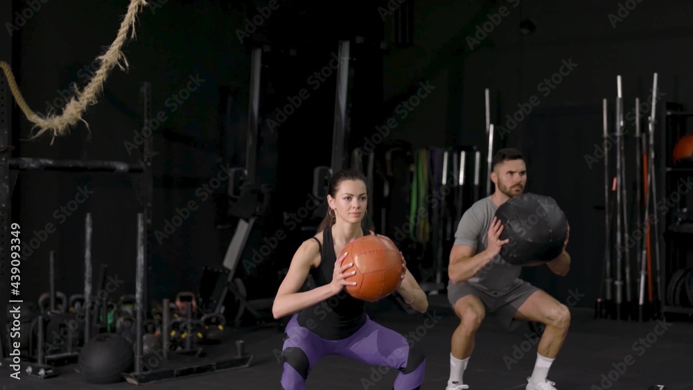 Beautiful young sports couple is working out with medicine ball in gym slow motion. Beautiful young sports couple is working out with medicine ball in gym slow motion.