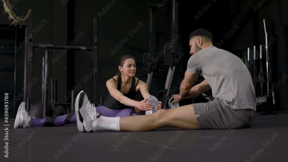 Portrait of a muscular couple doing leg stretchings slow motion. Portrait of a muscular couple doing leg stretchings slow motion.