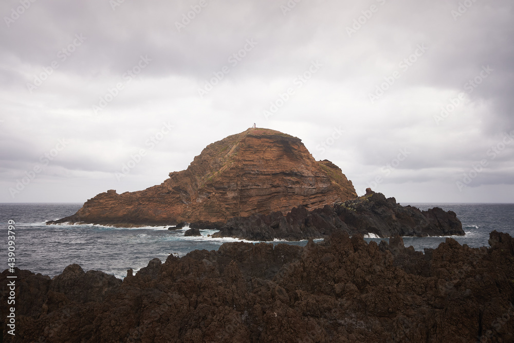 Ilhéu Mole island in Porto Moniz in Madeira, near natural swimming pools at cloudy day.