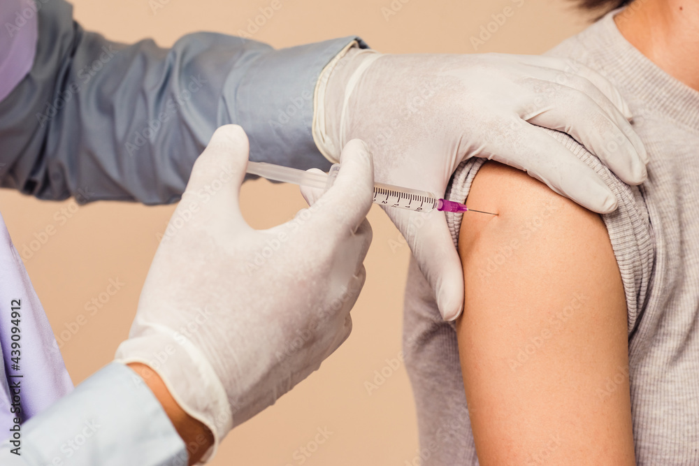 Closeup syringe during coronavirus (COVID-19) vaccination on arm.